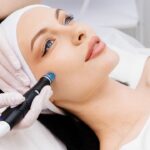 female cosmetologist performs a hydrafacial treatment on an attractive woman